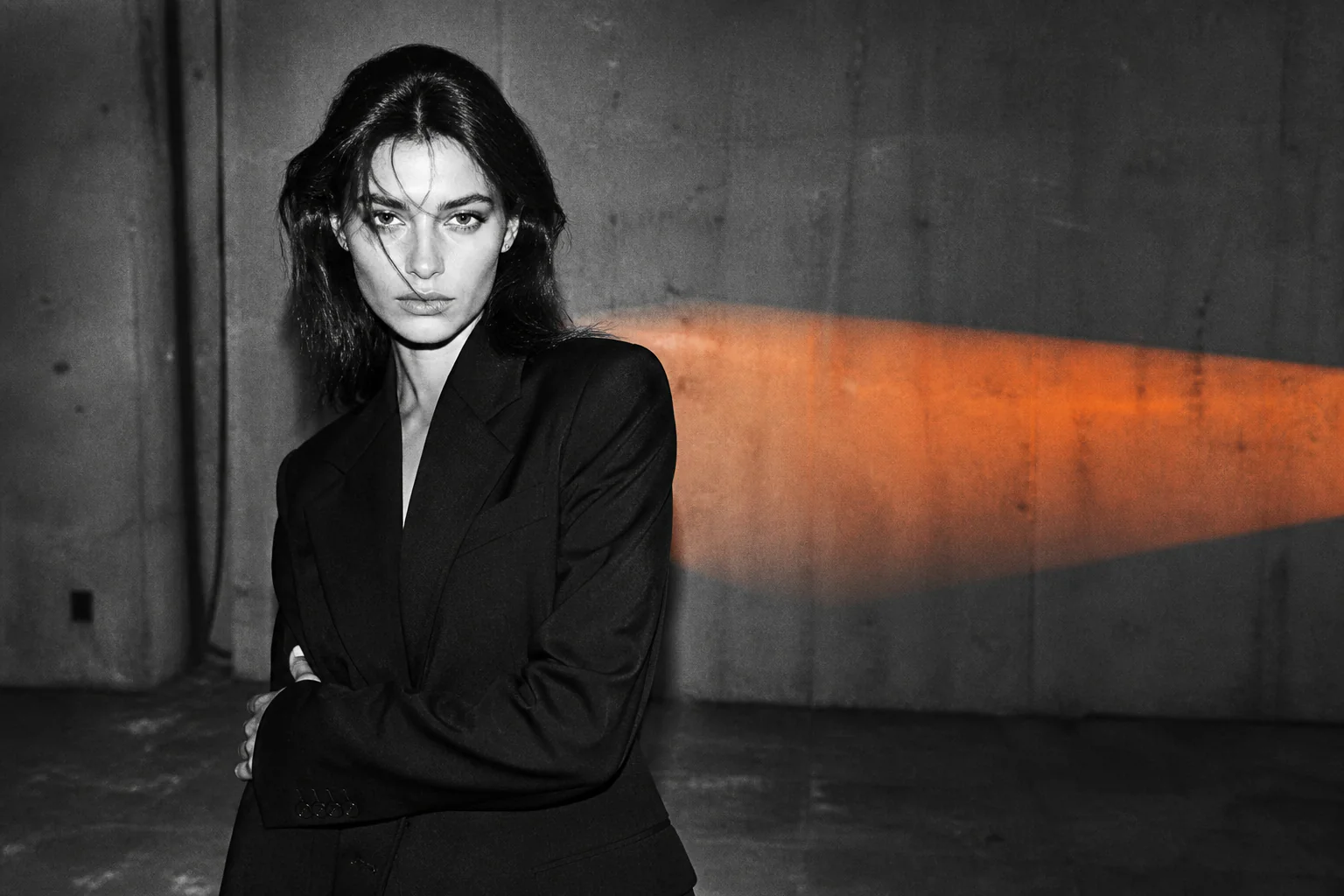 Black-and-white 35mm fashion portrait of an adult model with orange gel light